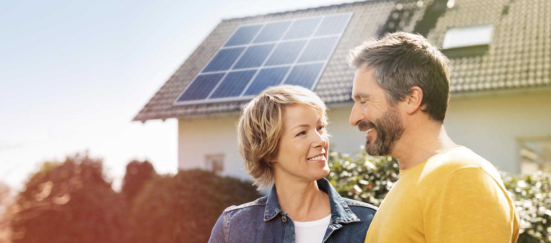 Paar steht vor Haus mit Photovoltaikanlage