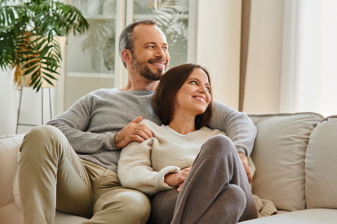 Paar sitzt lächelnd zusammen auf Couch 