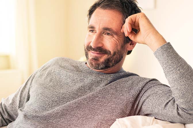 Mann sitzt gut gelaunt auf Couch
